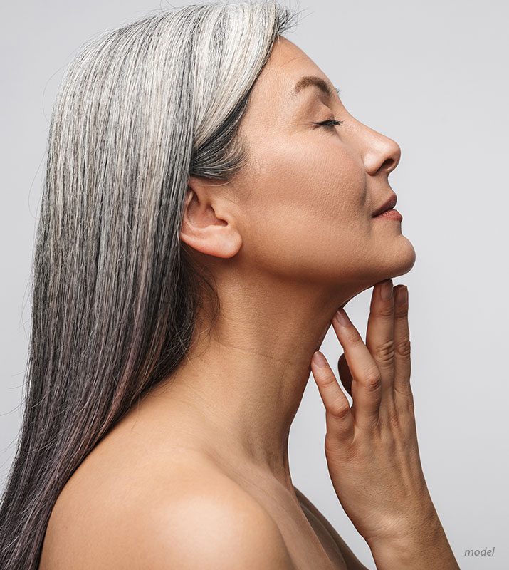 Profile view of middle aged woman peacefully caressing her chin