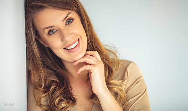 Smiling woman leaning her head on a wall