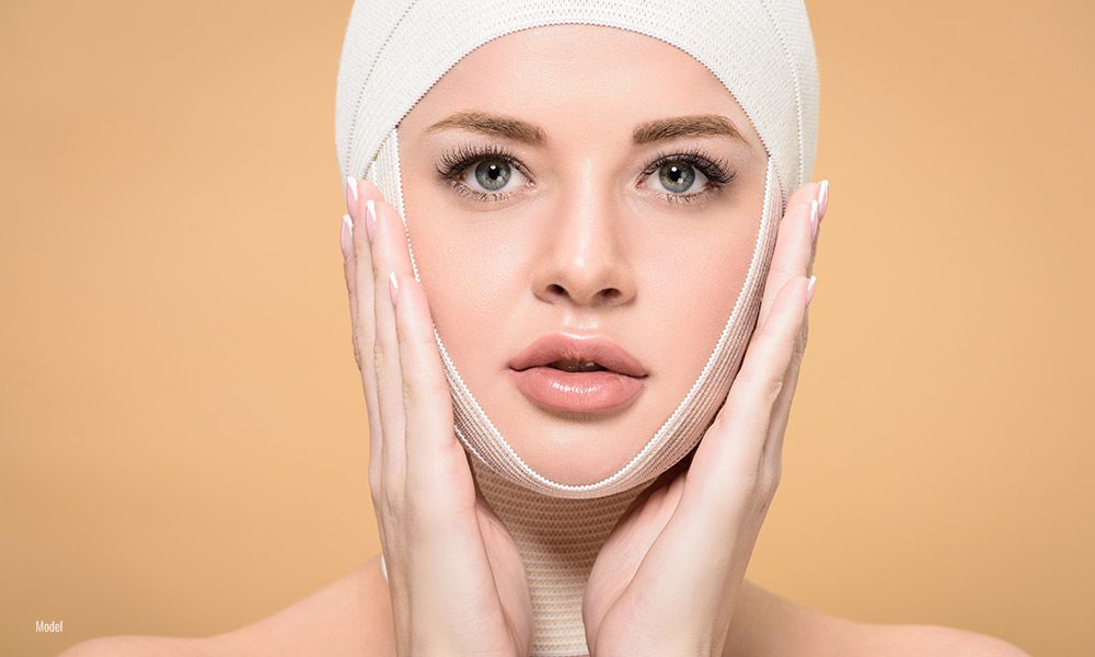 A beautiful woman's face with a gauze bandage draped over it.